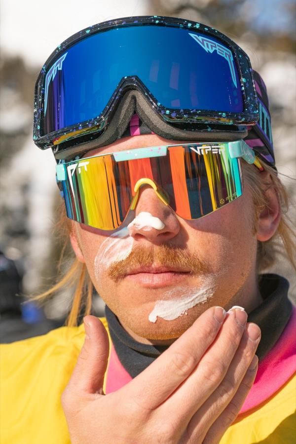 Person wearing snowboard attire and putting on sunscreen